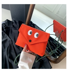 Détail du sac bandoulière en toile orange avec yeux de dessin animé et sangle