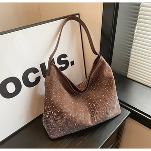 Dettaglio di una borsa hobo in pelle scamosciata marrone con strass argentati e stile retrò