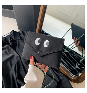 Détail du sac bandoulière en toile avec yeux de dessin animé et sangle tressée verte