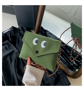 Détail du mini sac en toile verte avec motif yeux mignons et bandoulière tressée