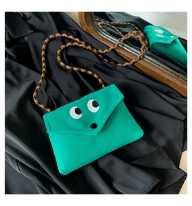 Détail du petit sac bandoulière vert avec motif yeux et sangle en corde tressée