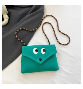 Détail du petit sac bandoulière vert en toile avec yeux et bandoulière tressée