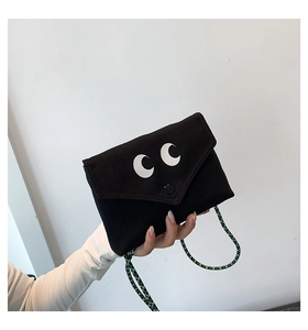 Détail du sac en toile noire avec imprimé yeux et bandoulière en corde tressée verte