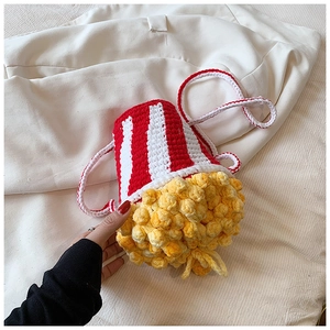 Close-up of handmade popcorn-shaped crochet bag with red and white knit textures