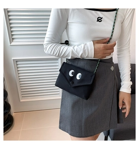 Détail d'un sac bandoulière en toile noire avec de grands motifs d'yeux de dessin animé