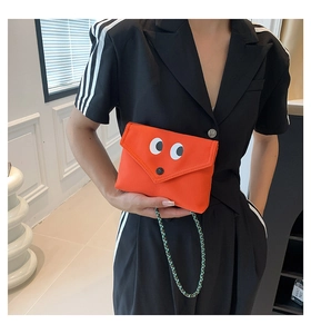 Détail du mini sac orange cartoon avec de grands yeux et une bandoulière tissée