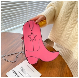 Detail of pink boot-shaped crossbody bag featuring stitched star and silver chain strap