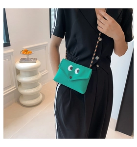 Gros plan du mini sac messager vert avec de grands yeux de dessin animé et bandoulière