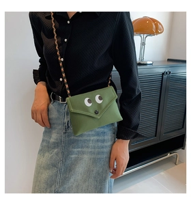 Détail du petit sac en toile verte avec yeux de dessin animé et bandoulière tissée colorée
