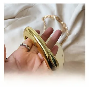 Close-up of golden metallic handle and polished glossy texture on round evening bag