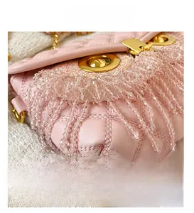 Détail macro du sac rose matelassé avec des franges en cristal et fermoir doré