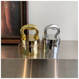 Close-up of sleek gold and silver acrylic cylinder clutch bags with metallic handles