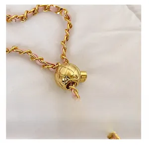 Détail de la bandoulière en cuir rose et chaîne dorée avec bille de réglage gravée