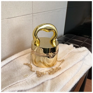 Detailed macro view of a glossy gold cylindrical mini bag with a round handle and chain strap
