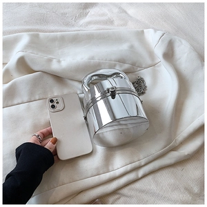 Size comparison of mini silver cylindrical box bag next to a mobile phone