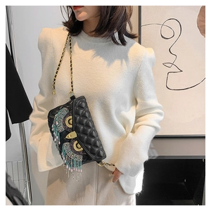 Détail de broderie hibou avec perles et glands sur un sac bandoulière matelassé noir