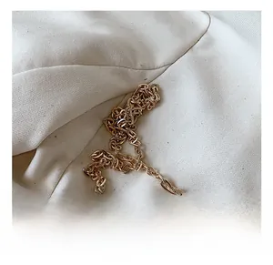 Macro detail of high-polish gold metal chain strap on minimalist cylinder bag