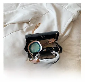 Top view of glossy black cylinder bag showing interior capacity with cosmetics and silver handle