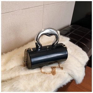 Detail of black cylindrical bag with large silver ring handle and gold chain strap