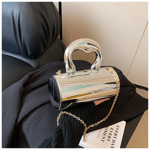 Detail of silver mirror cylinder bag with gold chain strap on dark background