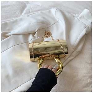 Detail of a luxury gold cylinder clutch bag with a mirror finish and chain strap