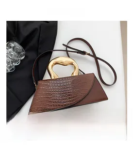 Close-up of retro brown crocodile texture handbag with unique gold liquid metal handle