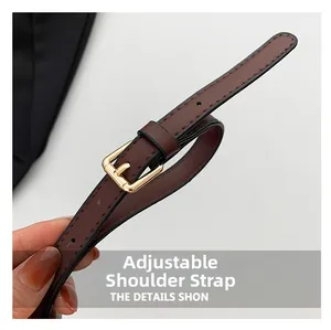 Detail of adjustable brown leather shoulder strap with golden metal buckle and stitching