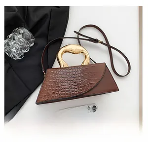 Detail view of brown crocodile texture trapezoid bag with liquid gold metal handle