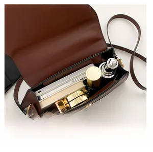 Internal capacity view of brown leather crossbody bag with makeup and smartphone inside