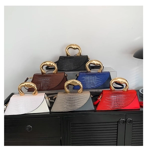 Close-up of trapezoid handbags featuring crocodile pattern and curved gold metal handles