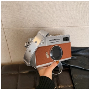 Detail of creative vintage camera crossbody bag with silver body and brown leather patch
