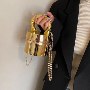 Glossy gold cylindrical box bag with sculptural metal handle and crossbody chain strap