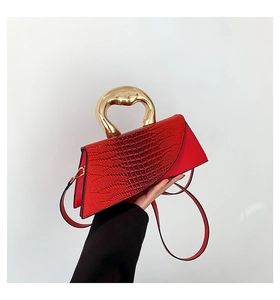 Detail of red stone texture handbag featuring a distinctive gold geometric metal handle