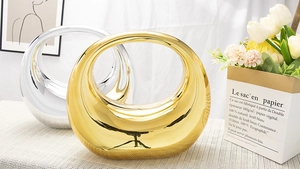 Détails de vases métalliques ronds or et argent sur un plateau de table épuré