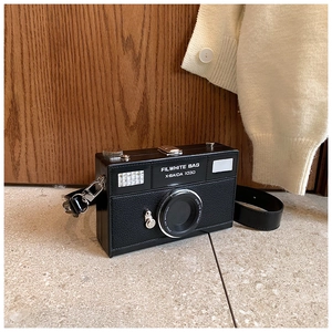 Detail of creative camera-shaped leather crossbody bag with realistic lens and strap