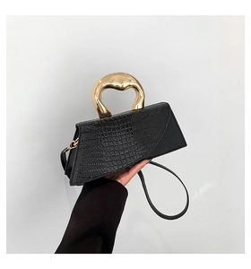 Detail of stone pattern texture and golden irregular handle on black crossbody bag