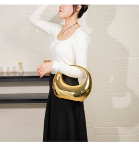 Vue détaillée du sac hobo doré à effet miroir porté par un mannequin au bras