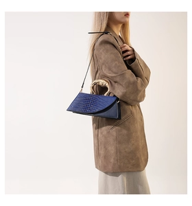 Detail of the unique gold sculptural handle and croc-embossed texture on the navy bag