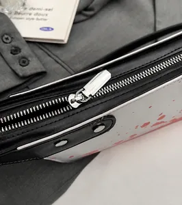 Detail of silver metal zipper and hardware on blood-splattered crossbody knife bag