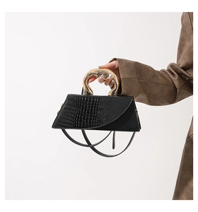 Detail of black crocodile texture handbag with unique gold irregular metal handle