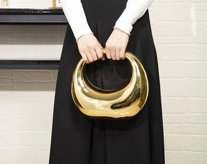 Détail d'un sac en acrylique miroir doré avec finition métal liquide et poignée élégante