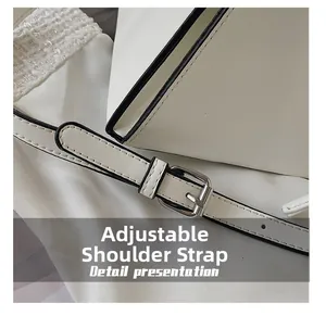 Detail of adjustable leather strap with silver metal buckle on a white triangle bag