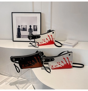 Artistic display of cleaver-shaped crossbody bags in black and white with red splatter