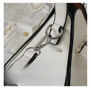 Close-up of white synthetic leather triangle bag with silver lobster clasp and D-ring