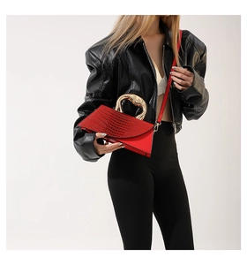 Detail of red crocodile texture handbag with unique gold metal handle and shoulder strap