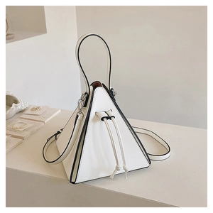 Close-up of a white triangular pyramid bag with black piping and drawstring closure detail