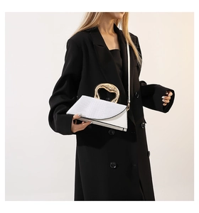 Chic white croc-embossed bag with unique gold handle shown on a black suit blazer