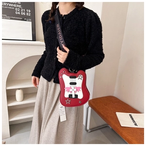 Detail of creative violin-shaped red PU bag with studded star accents and wide logo strap