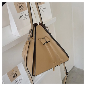 Macro detail of a beige geometric triangle leather handbag with black edge paint details