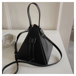 Detail of black pyramid bag showing smooth faux leather texture and silver hardware